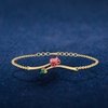 14K gold bracelet with a rose shaped design and a green stone 