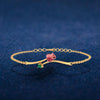 A 18K gold bracelet featuring a green stone and a rose-shaped design 